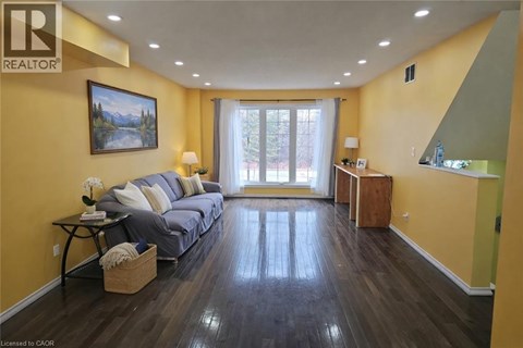 A living room with a grey sofa and a painting on the wall.