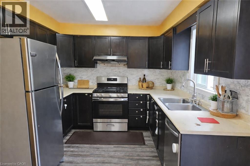 A kitchen with black cabinets and a stainless steel refrigerator.