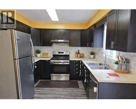 A kitchen with black cabinets and a stainless steel refrigerator.