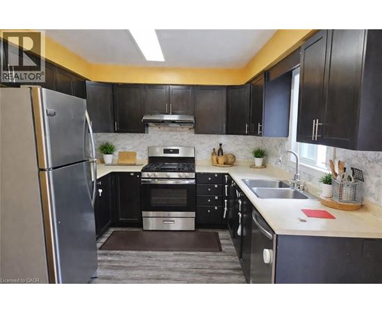 A kitchen with black cabinets and a stainless steel refrigerator.