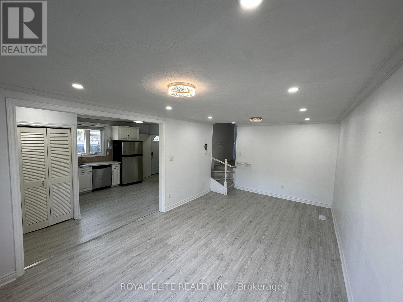 A spacious room with wooden flooring and white walls, with a door leading to another room visible in the background.