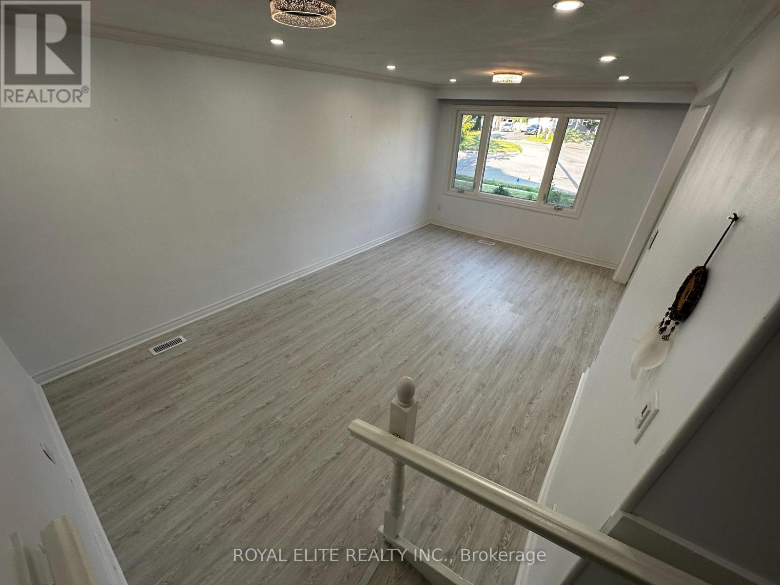 A room with wooden flooring and a window overlooking a street.
