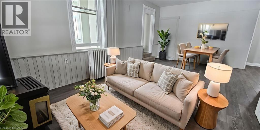 A living room with a beige couch, a coffee table with a vase of flowers, and a lamp on a side table.