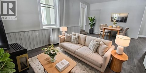 A living room with a beige couch, a coffee table with a vase of flowers, and a lamp on a side table.