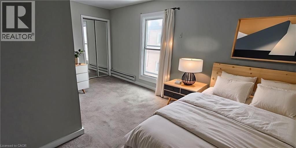 A bedroom with a bed, nightstand, and a painting on the wall.