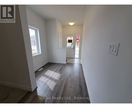 A room with wooden flooring and white walls, with a window on the left and a door on the right.
