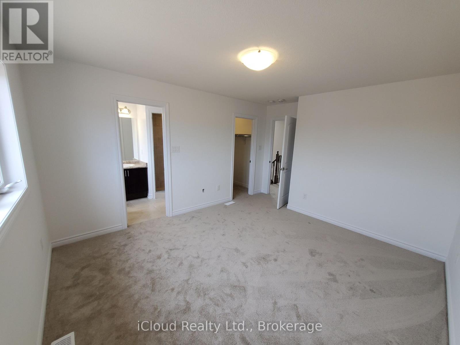 A spacious room with a carpeted floor and white walls.