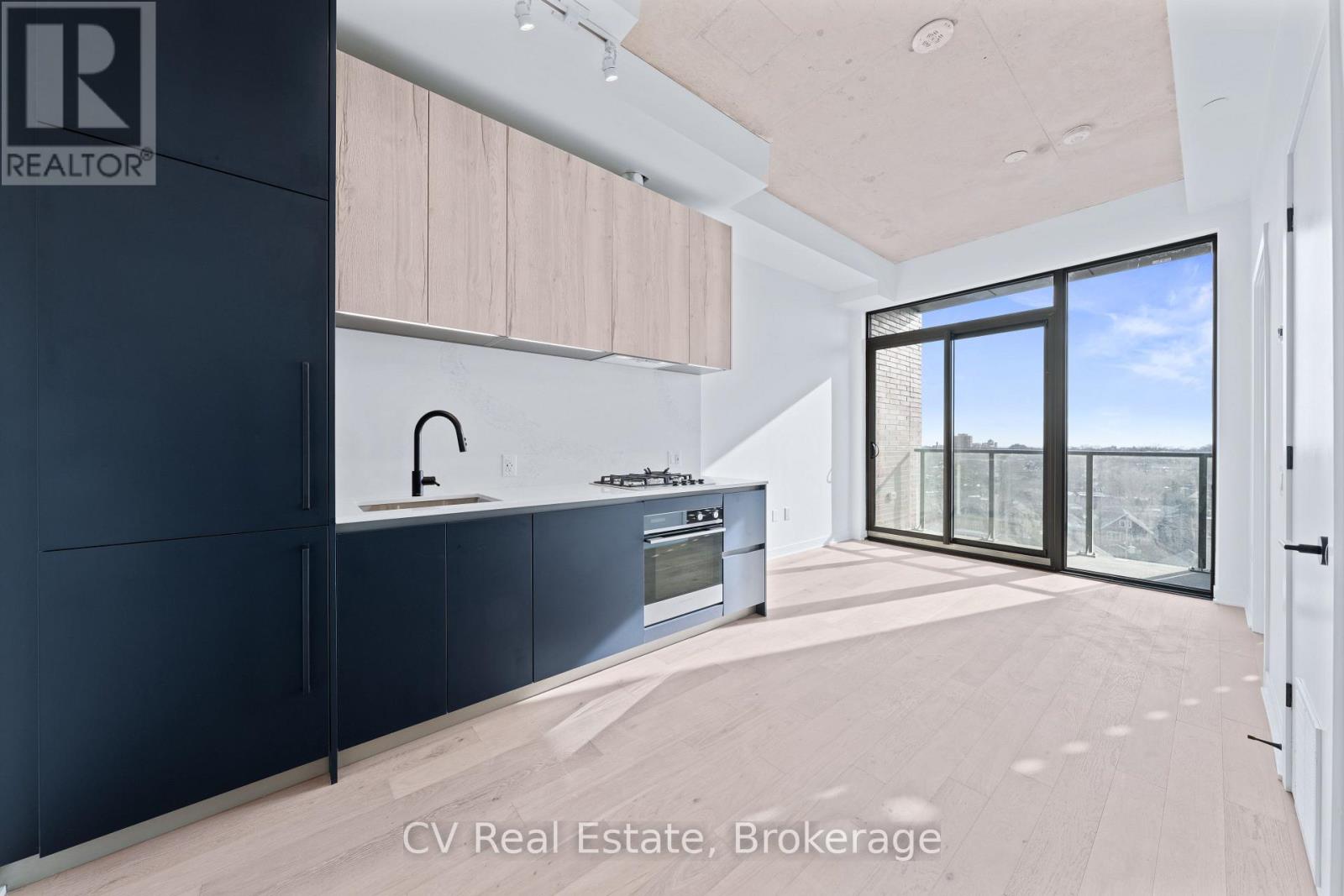A modern kitchen with black cabinets and a large window.