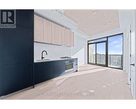 A modern kitchen with black cabinets and a large window.