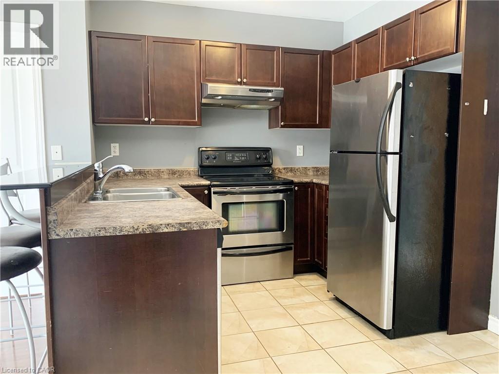 A kitchen with brown cabinets and a black refrigerator.