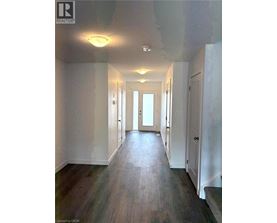 A long hallway with white walls and wood flooring.