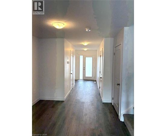 A long hallway with white walls and wood flooring.