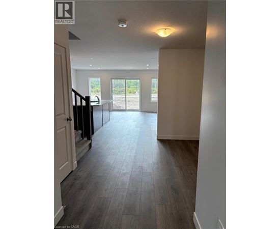 A spacious room with a wooden floor and a glass door leading outside.