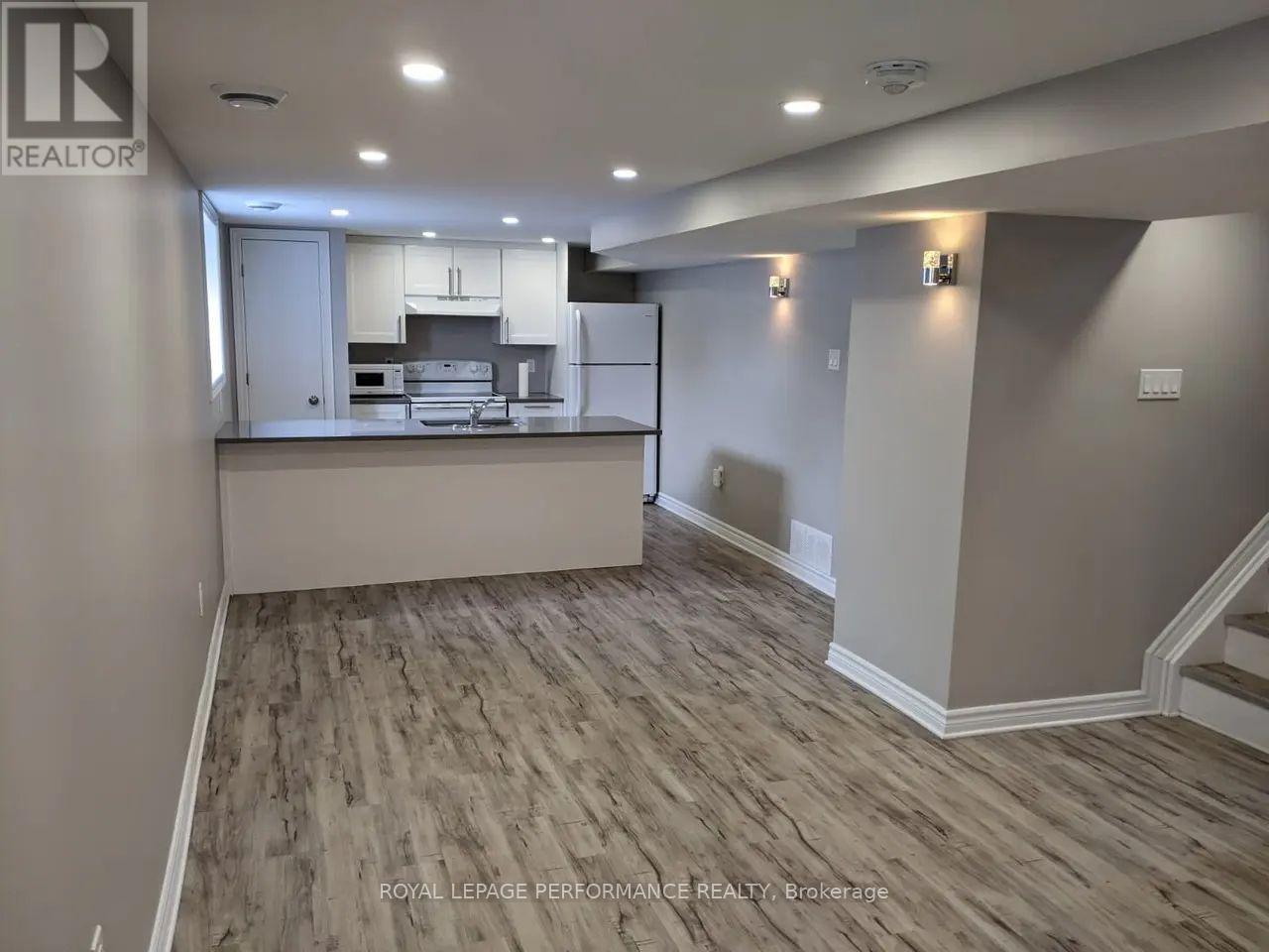 A spacious room with a kitchen island and wood flooring.