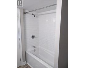 A white bathroom with a white tub and white tiles.
