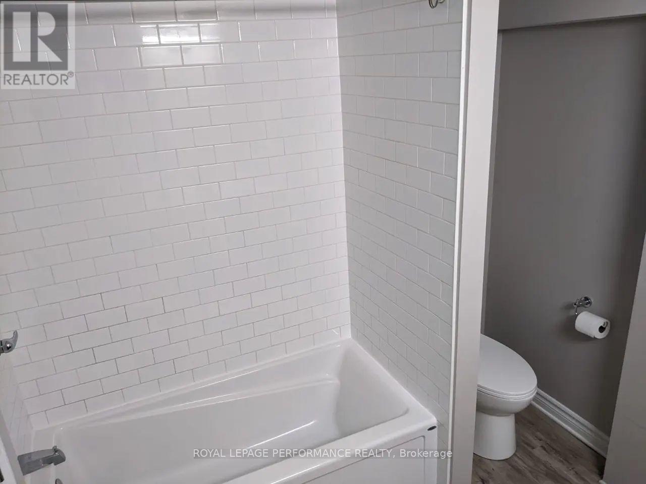 A white bathroom with a tub and toilet.