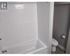 A white bathroom with a tub and toilet.