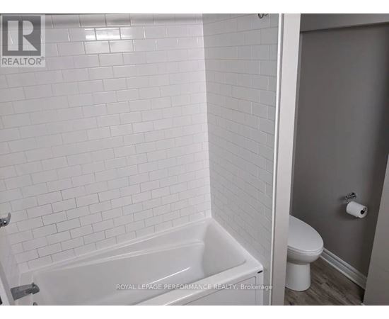 A white bathroom with a tub and toilet.