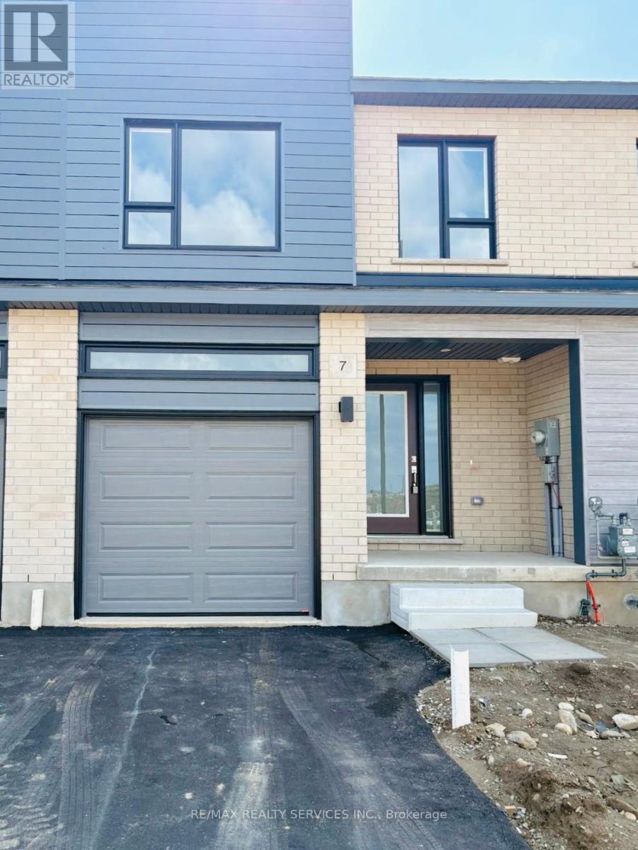 A modern house with a grey garage door is for sale.