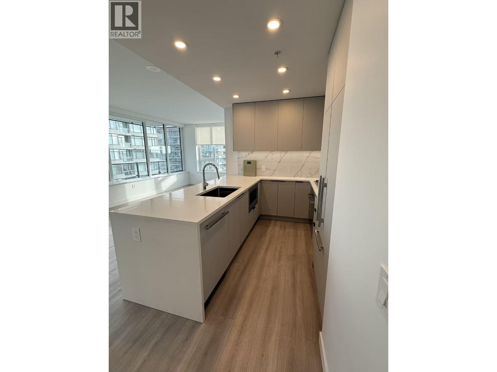 A modern kitchen with white cabinets and a wooden floor.