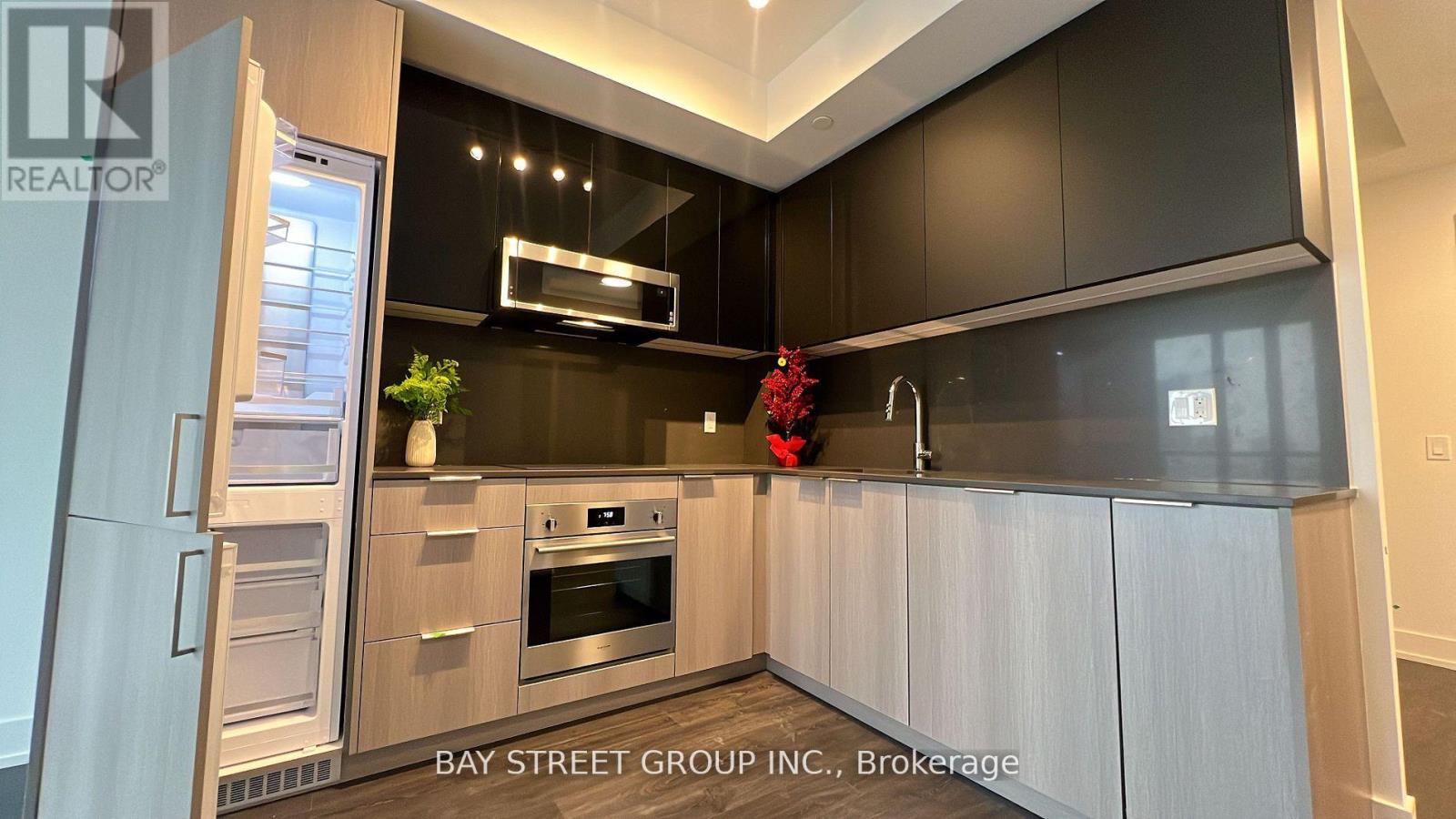 A modern kitchen with a refrigerator, oven, and microwave.