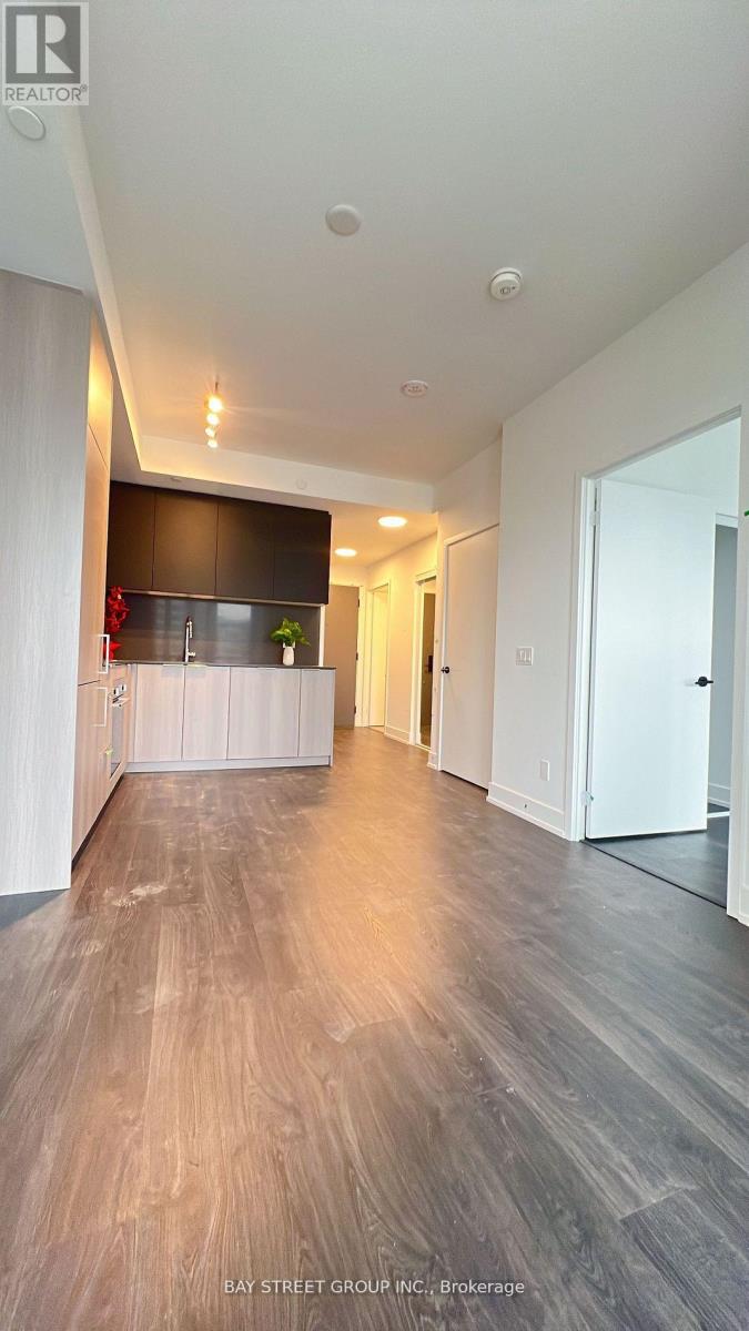A spacious room with wooden flooring and a white door on the right.