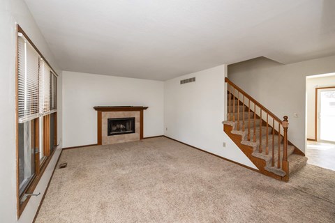 A living room with a fireplace and a staircase.