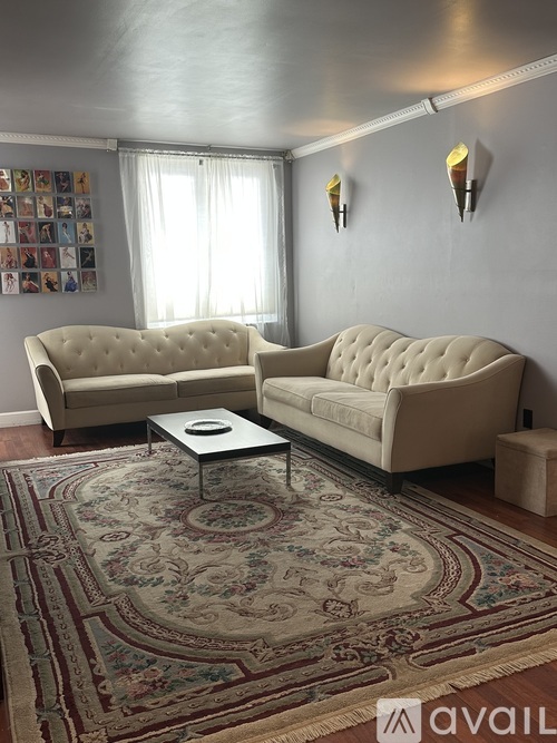 A living room with two beige sofas and a floral rug.