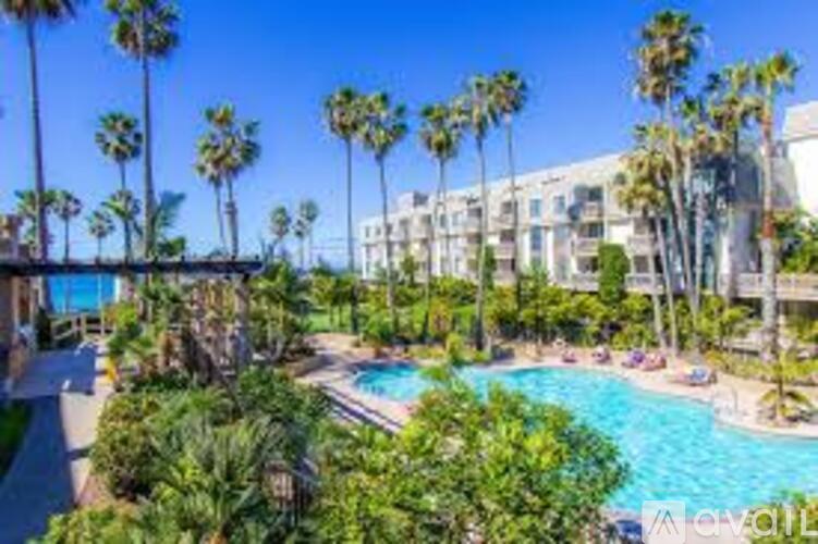 A pool surrounded by palm trees and a building in the background.