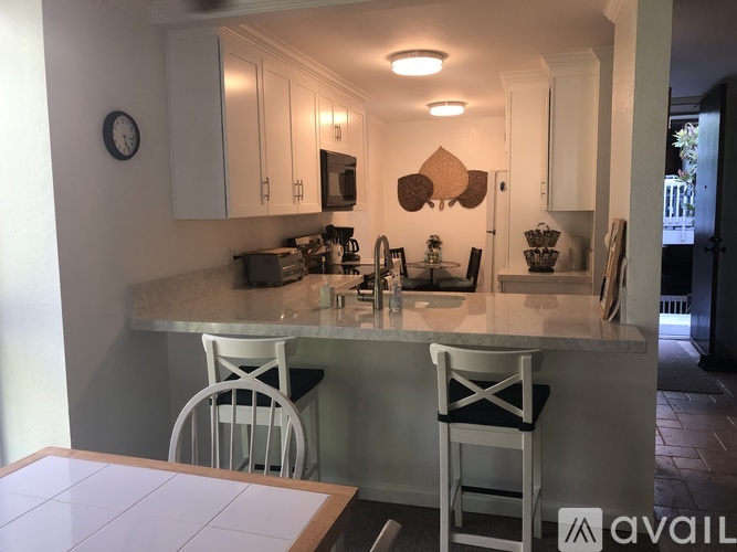 A kitchen with a white counter and two chairs.