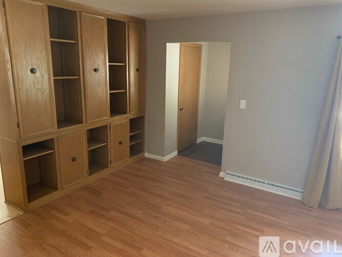 A room with wooden floors and a large wooden cabinet with glass doors.