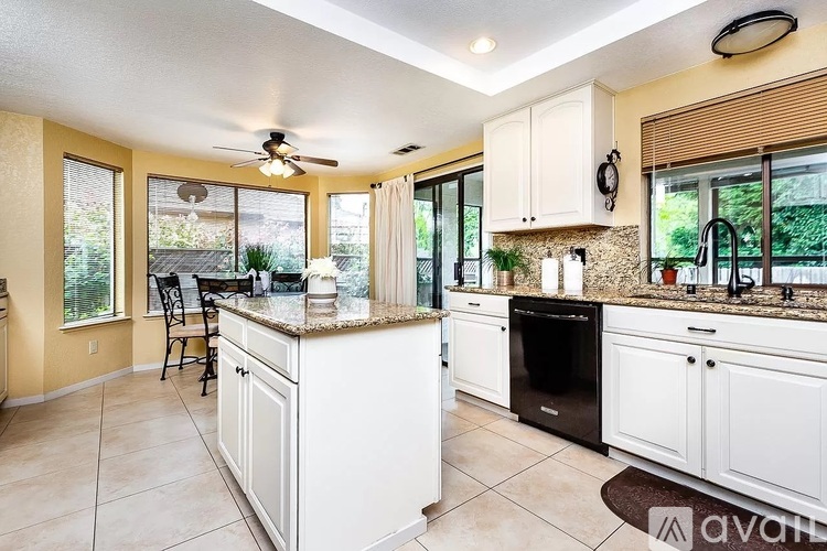 A kitchen with white cabinets and a brown countertop.