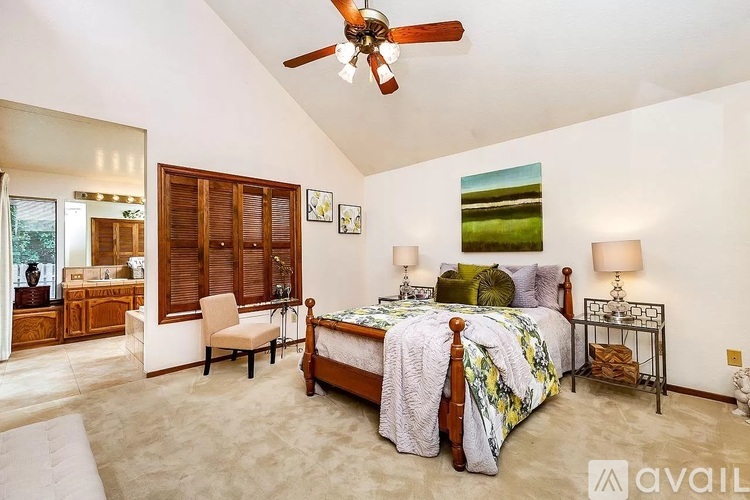 A bedroom with a bed, chair, and a ceiling fan.