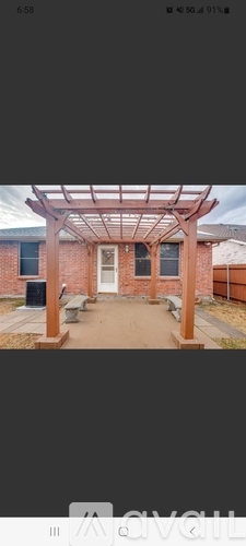 A pergola is attached to a brick building.