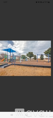 A playground with a blue swing set and a sandy area.