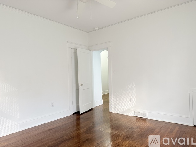 A spacious room with wooden floors and white walls.