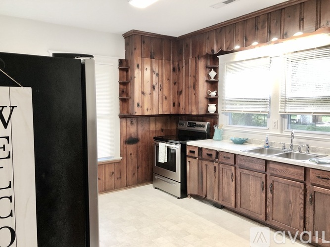 A kitchen with wooden cabinets and a black refrigerator.