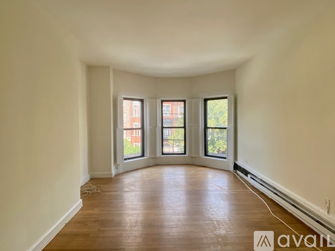 A room with wooden floors and three windows.