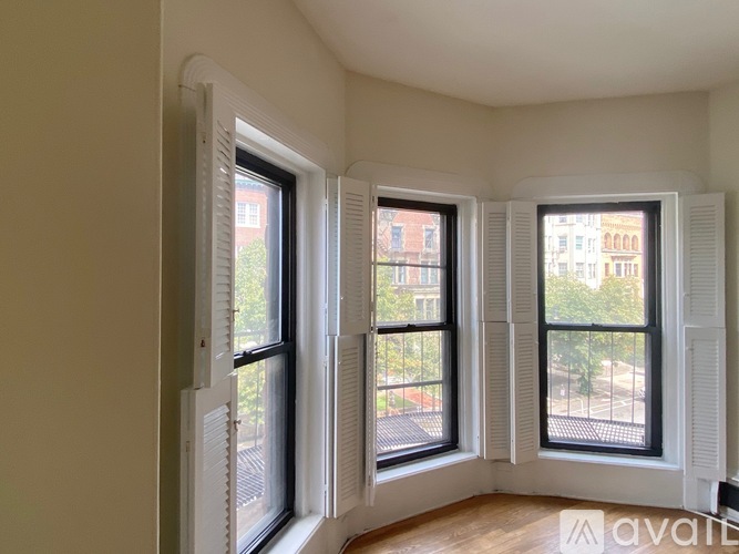Three windows with white frames and shutters in a room.