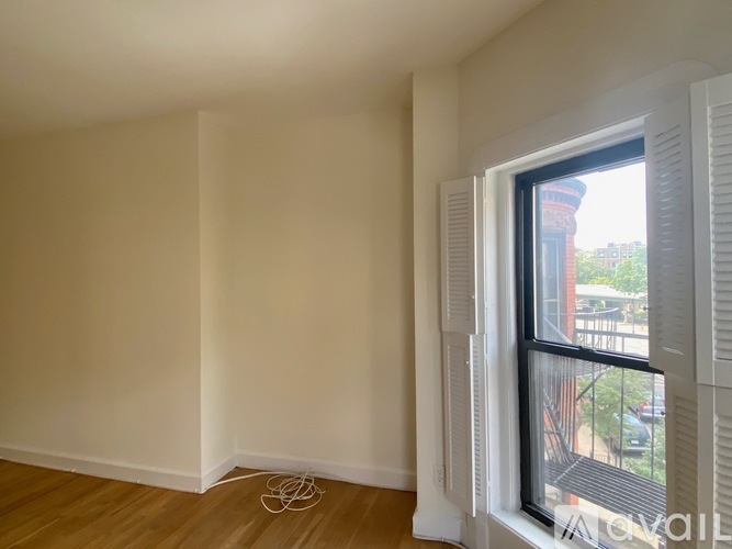 A room with a window and a wooden floor.