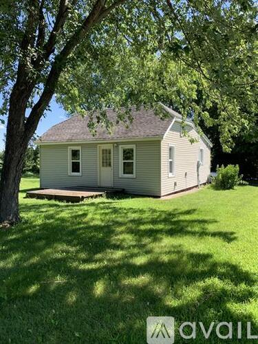 A house with a porch and a tree in front of it.