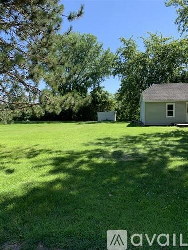 A house is located in a grassy area with trees in the background.