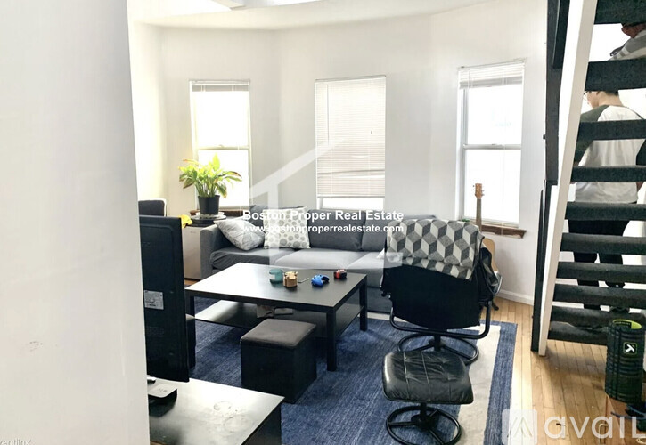 A living room with a couch, chairs, and a television.