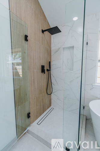 A modern bathroom with a glass shower door and a marble wall.