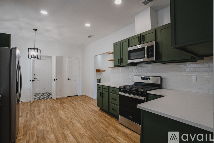 A kitchen with green cabinets and a black fridge.
