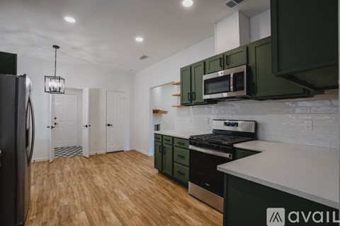 A kitchen with green cabinets and a black fridge.