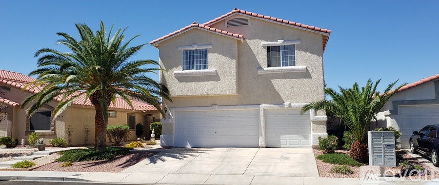 A two-story house with a garage and palm trees in front.