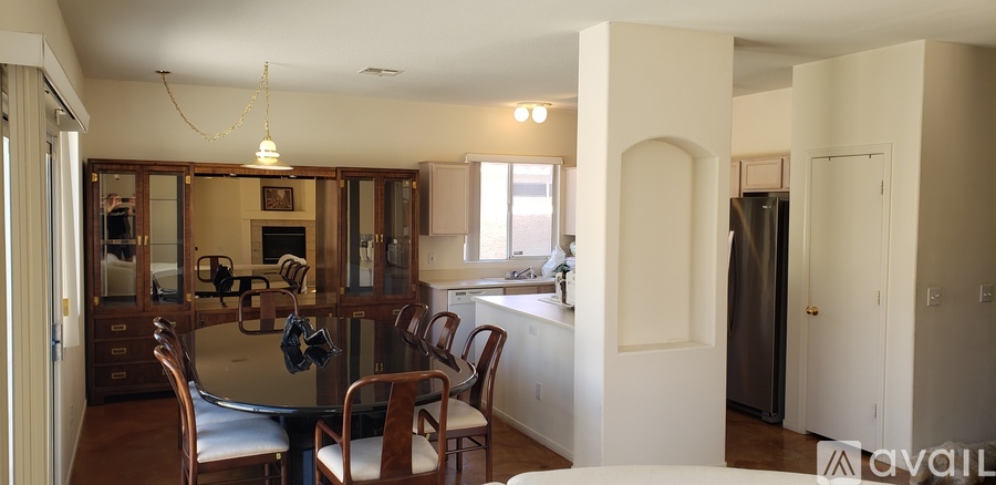 A kitchen with a table and chairs in the foreground and a refrigerator in the background.