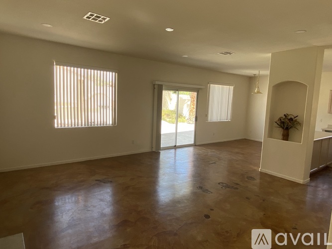 A spacious room with wooden flooring and large windows.