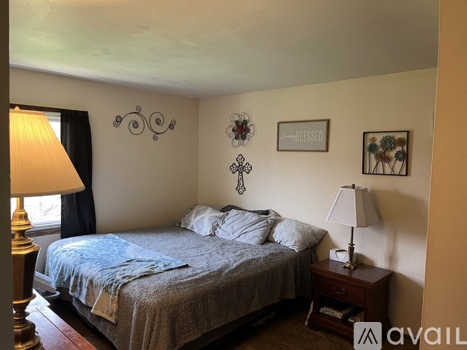 A bedroom with a bed, two lamps, and a painting on the wall.